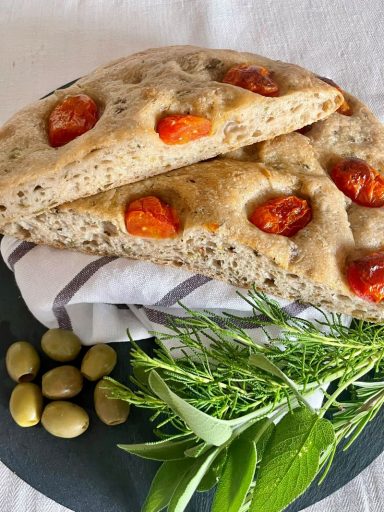 Oliven-Tomaten-Focaccia Saftig-knusprige Focaccia mit Tomaten auf der Oberfläche. Italienische Kräuter und Oliven im Teig ergeben einen würzigen Geschmack.